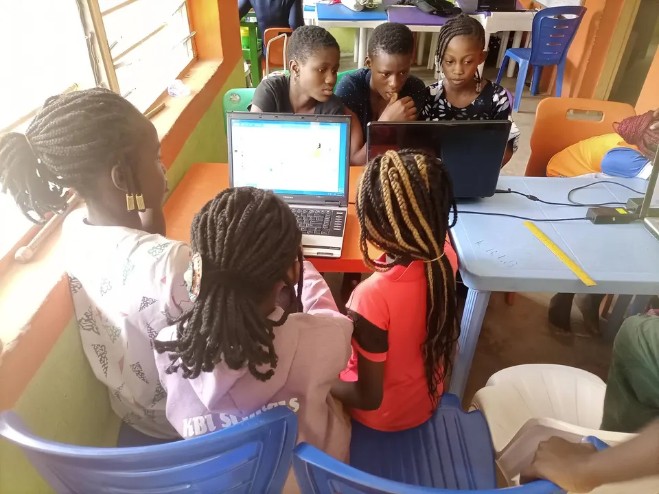 Children gathered around laptops at a community learning centre