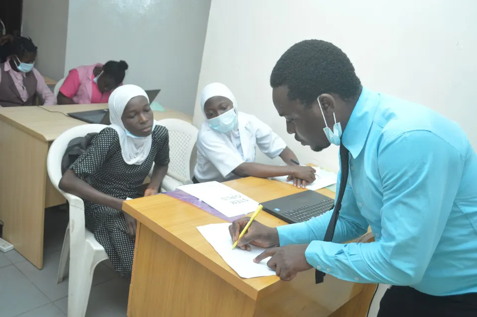 An instructor mentoring two girls one-on-one at a desk during International Day of the Girl 2021
