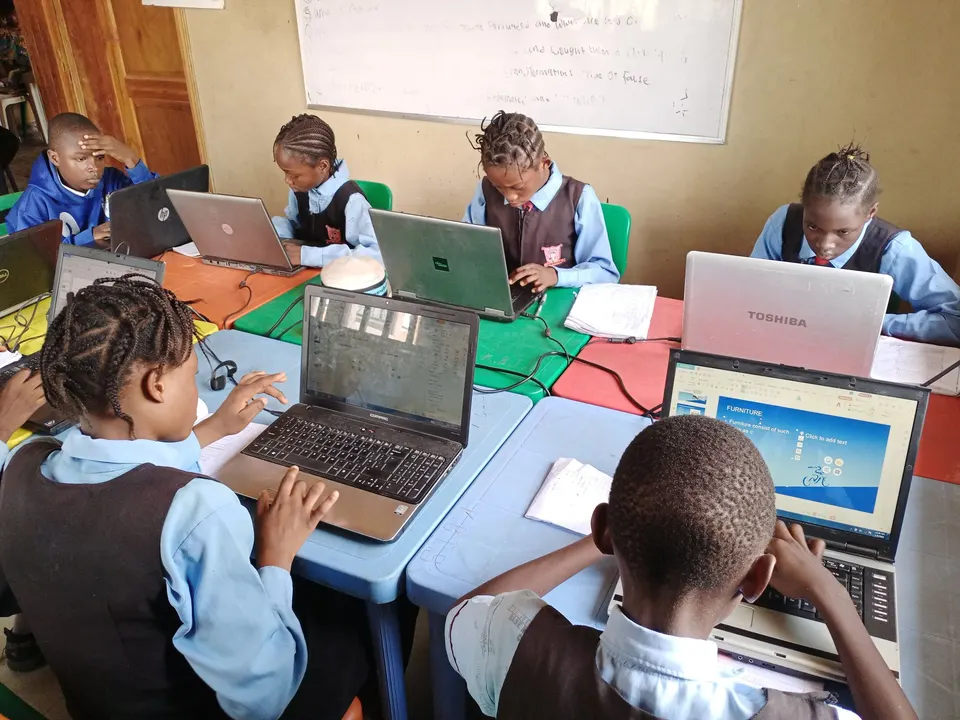 Pupils in school uniform coding on laptops at Knowledge Base International Schools